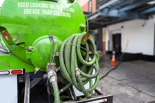 grease trap being pumped out by service technician in Amherst