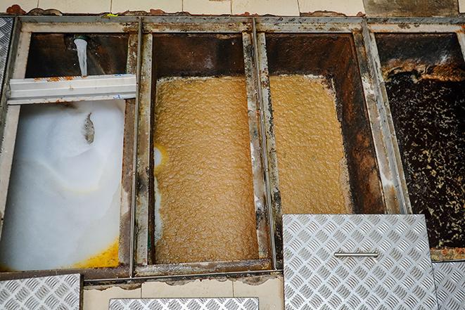 professional cleaning technician servicing a grease trap